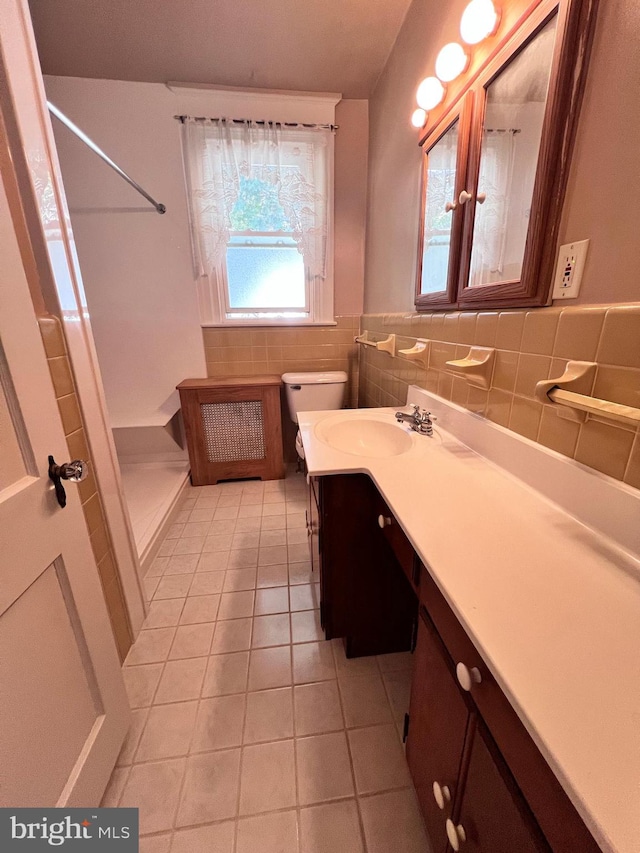 bathroom with tile walls, walk in shower, vanity, tile patterned flooring, and toilet