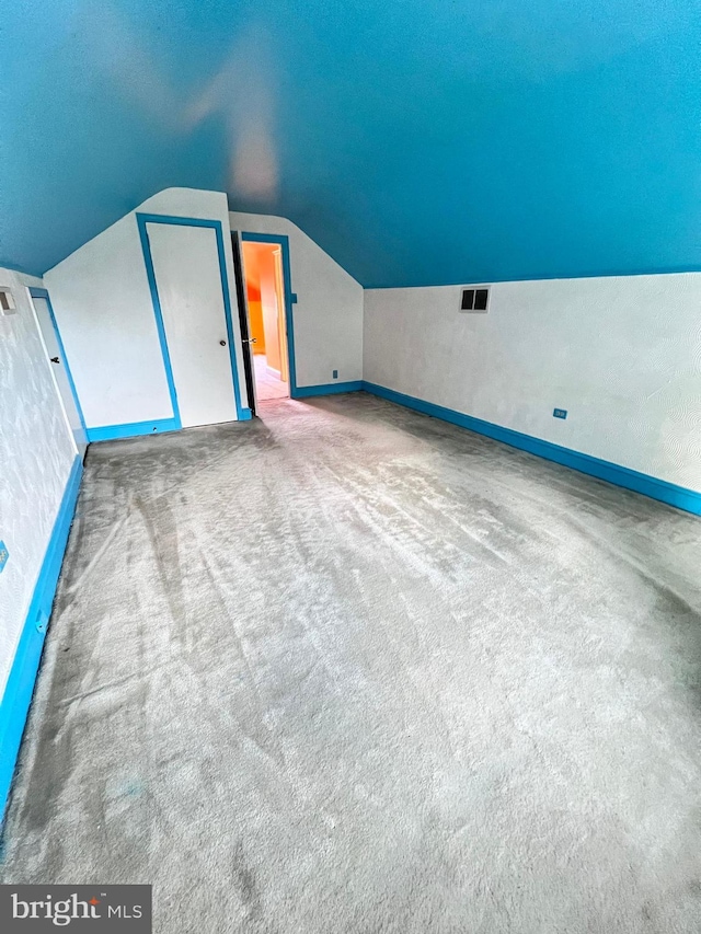 additional living space with lofted ceiling, a textured ceiling, and light carpet