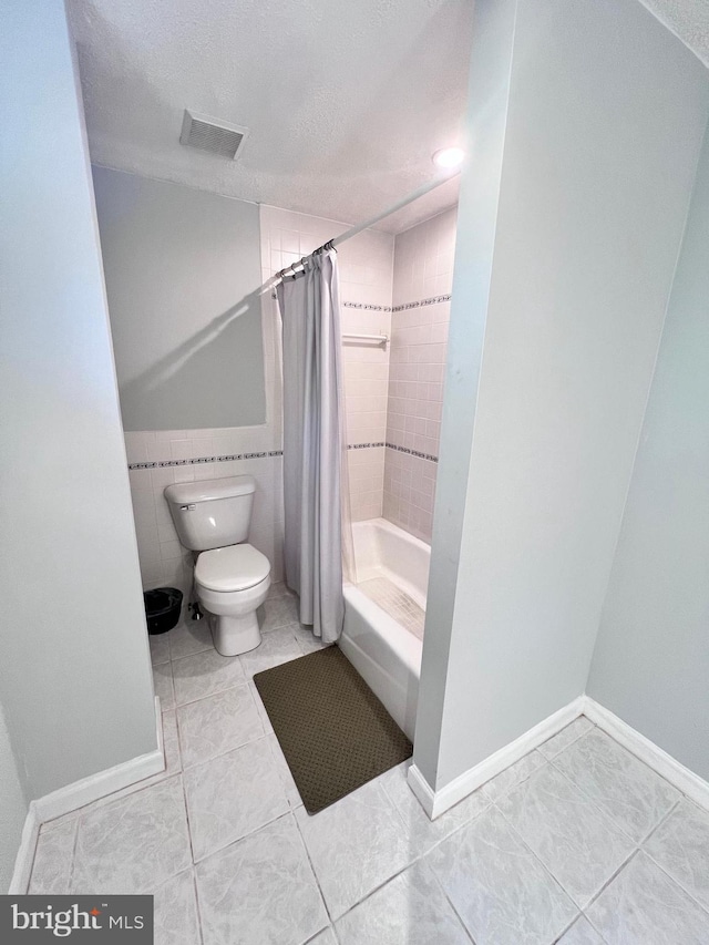 bathroom featuring tile patterned floors, shower / bath combo, a textured ceiling, and toilet