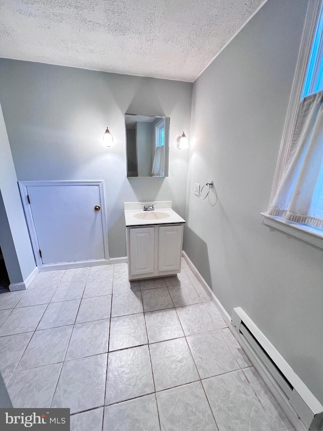 bathroom with tile patterned flooring, a baseboard radiator, vanity, and a textured ceiling