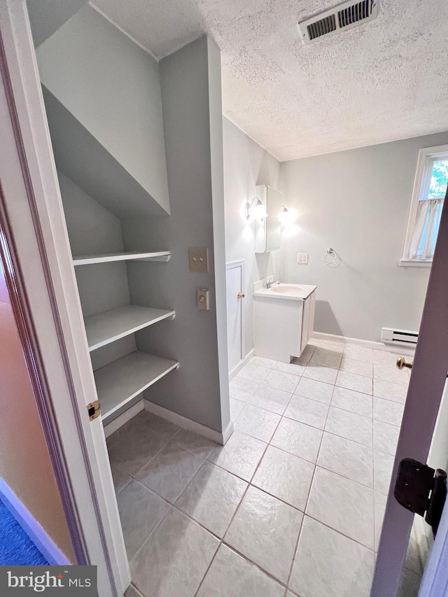 bathroom featuring vanity, tile patterned flooring, a textured ceiling, and a baseboard heating unit