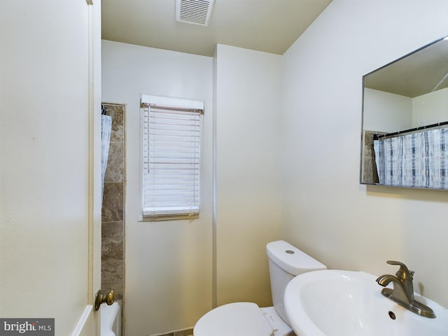 bathroom featuring a shower with curtain, sink, and toilet