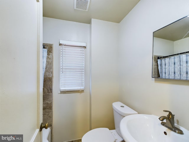 bathroom with a sink, toilet, and curtained shower