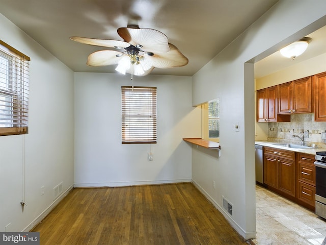 kitchen featuring appliances with stainless steel finishes, a sink, a ceiling fan, light countertops, and decorative backsplash