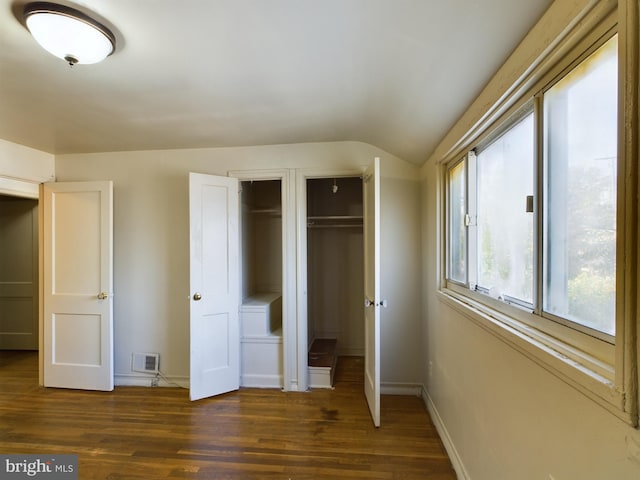 unfurnished bedroom featuring lofted ceiling, dark wood-style floors, and baseboards