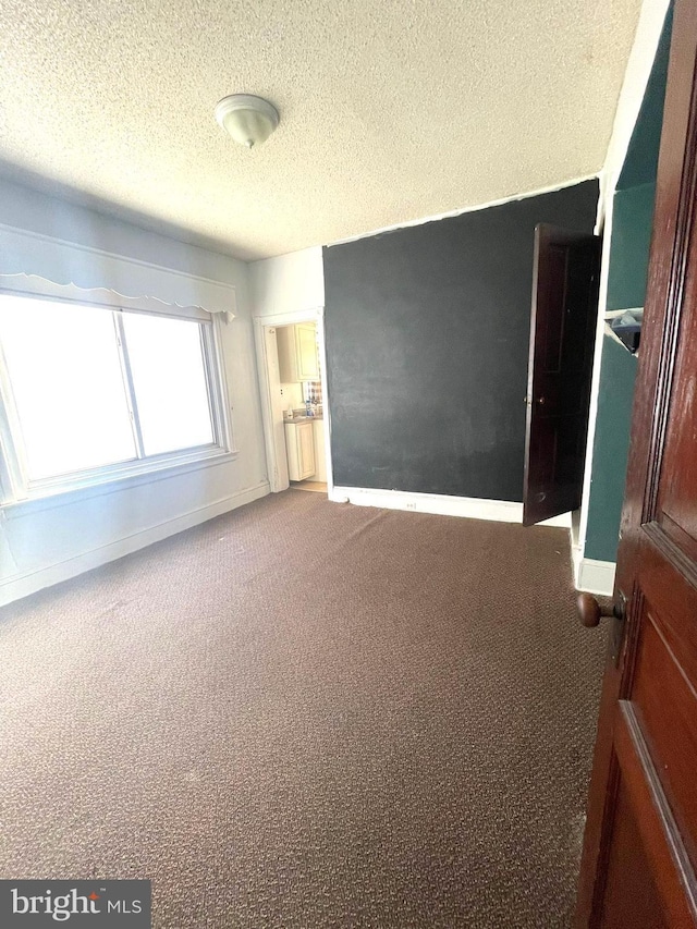 unfurnished bedroom with a textured ceiling and carpet floors