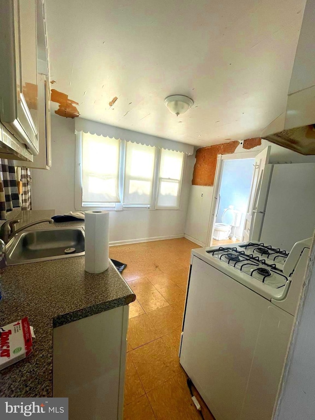 kitchen with sink, white gas range, and white cabinets