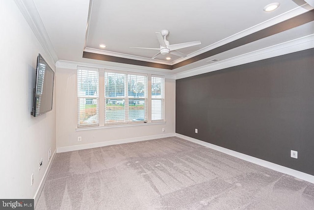 carpeted empty room featuring a tray ceiling, ceiling fan, and crown molding