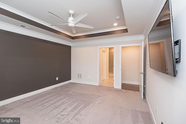 interior space with a tray ceiling, ceiling fan, light colored carpet, and ornamental molding