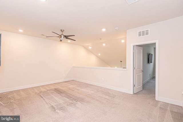 carpeted spare room featuring vaulted ceiling and ceiling fan