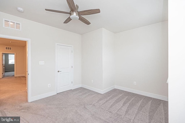 empty room featuring ceiling fan and light colored carpet