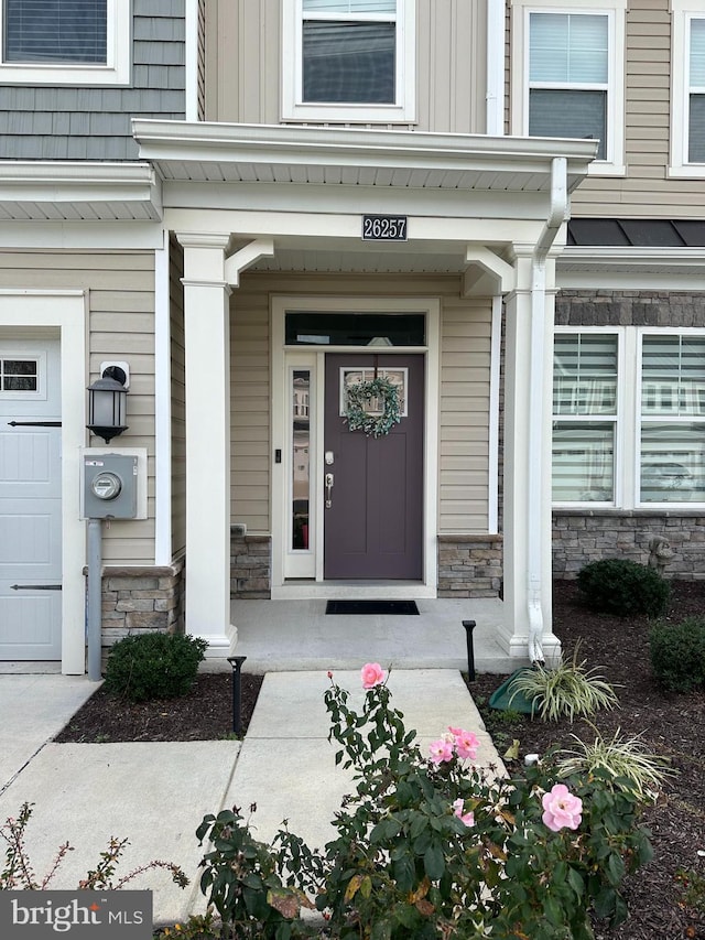 view of exterior entry featuring a porch and a garage