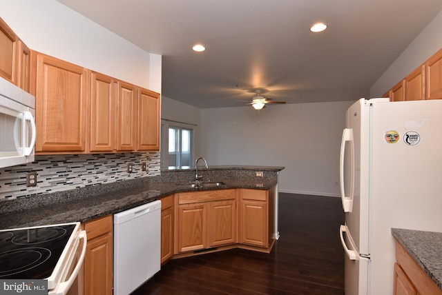 kitchen featuring sink, kitchen peninsula, tasteful backsplash, white appliances, and dark hardwood / wood-style flooring