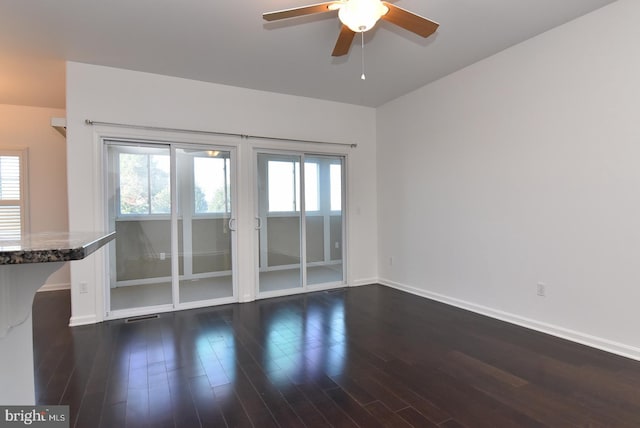 unfurnished room featuring a wealth of natural light, dark wood-type flooring, and ceiling fan