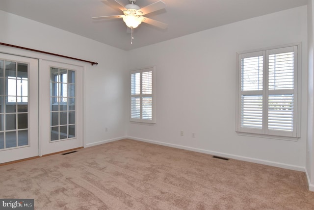 spare room with ceiling fan, plenty of natural light, and light carpet