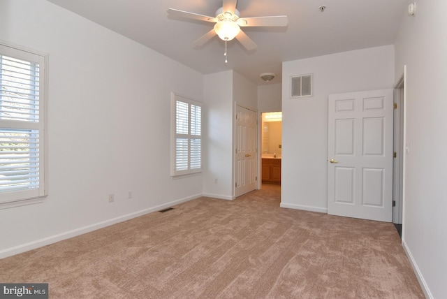 unfurnished bedroom featuring ensuite bathroom, light carpet, ceiling fan, and a closet