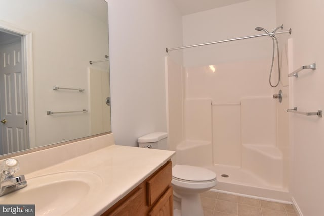 bathroom with tile patterned flooring, vanity, toilet, and a shower