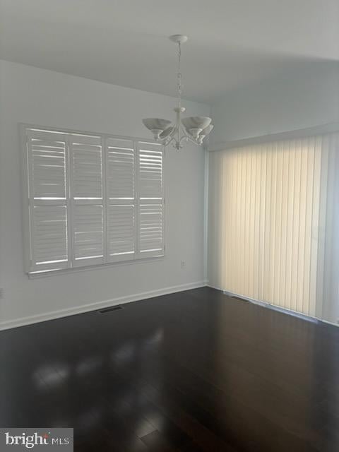 unfurnished room featuring wood-type flooring and a notable chandelier