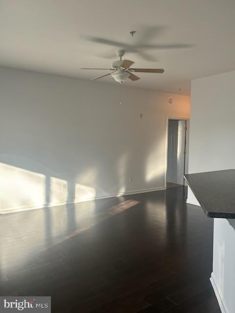 unfurnished room with dark wood-type flooring and ceiling fan