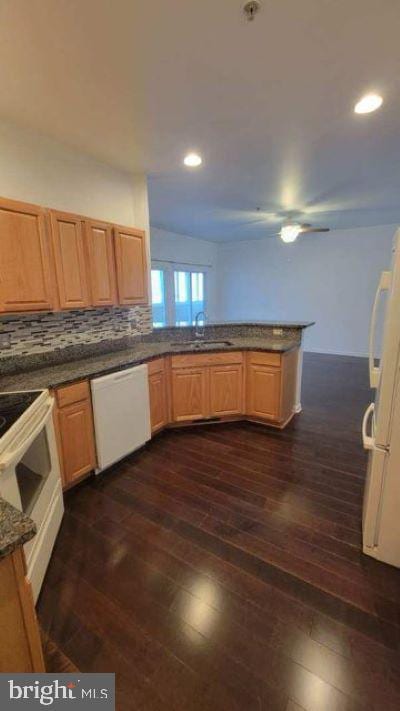 kitchen with white appliances, decorative backsplash, sink, dark wood-type flooring, and kitchen peninsula