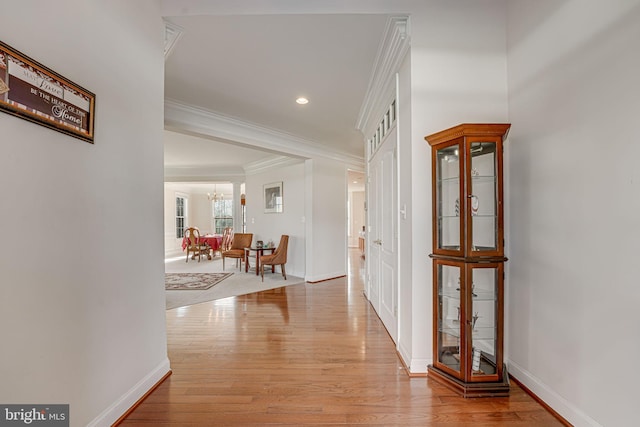 hallway featuring a chandelier, crown molding, and light hardwood / wood-style flooring