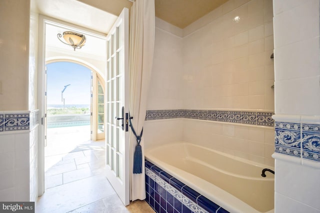 bathroom featuring tile walls and a relaxing tiled tub