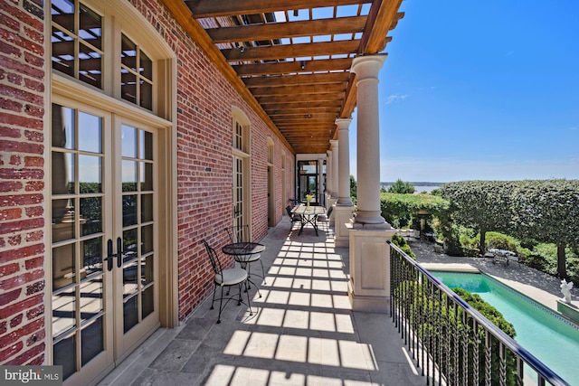 balcony with a patio, a pergola, and french doors