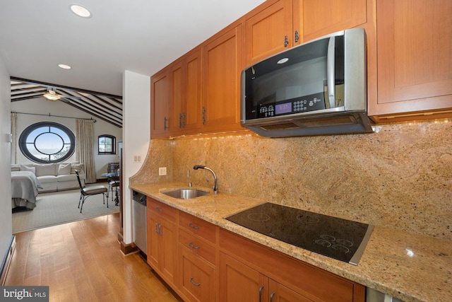 kitchen featuring stainless steel appliances, lofted ceiling, sink, light stone countertops, and light hardwood / wood-style flooring