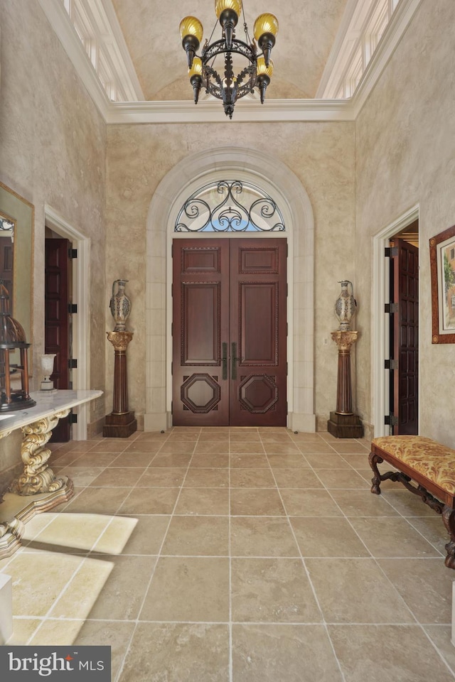 entrance foyer featuring a high ceiling, a chandelier, and ornamental molding