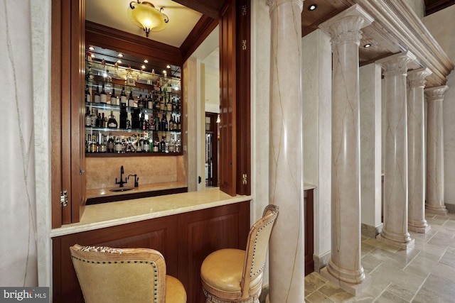 bar with sink, crown molding, and decorative columns