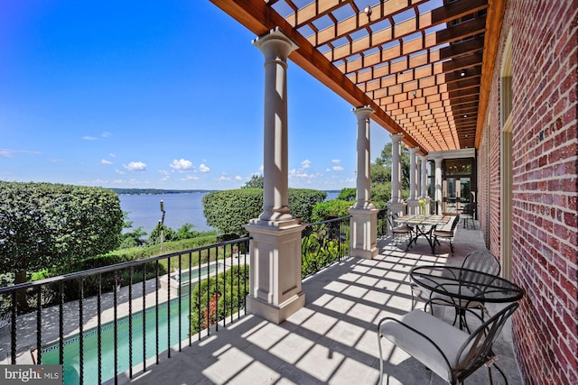 view of patio with a water view, a pergola, and a balcony