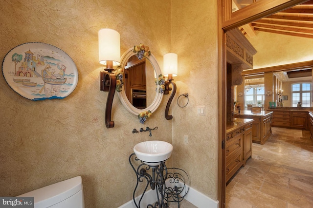 bathroom featuring vanity, vaulted ceiling with beams, and toilet