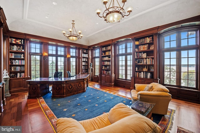 office featuring built in shelves, hardwood / wood-style flooring, crown molding, and an inviting chandelier