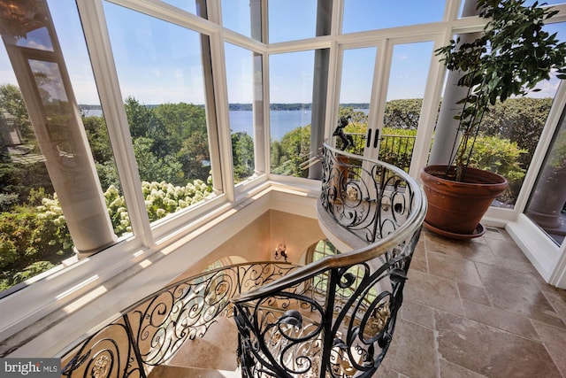 sunroom featuring a water view