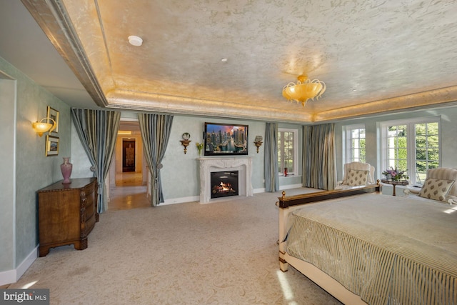 bedroom featuring a premium fireplace, a raised ceiling, and carpet floors