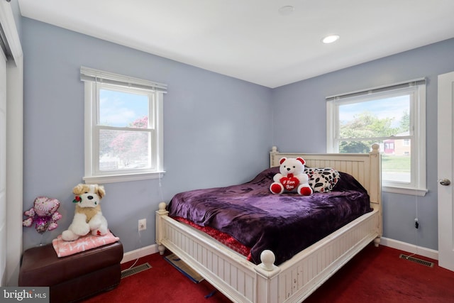 bedroom with multiple windows and dark carpet