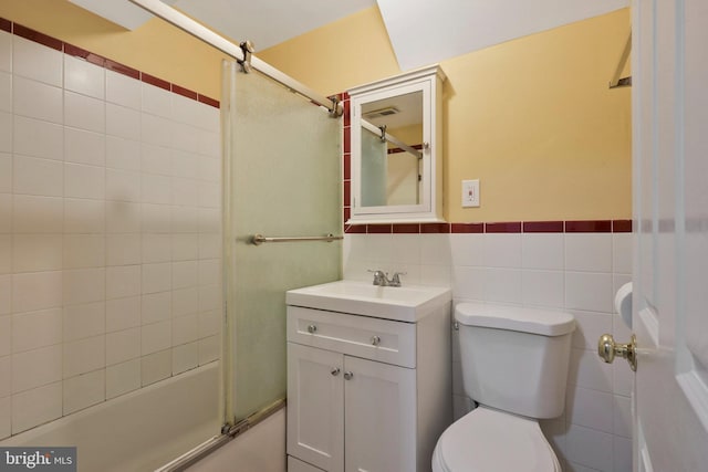 full bathroom featuring toilet, vanity, tile walls, and shower / bath combination with glass door