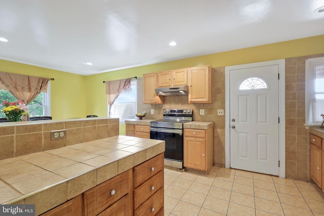 kitchen featuring stainless steel electric stove, tile countertops, and plenty of natural light