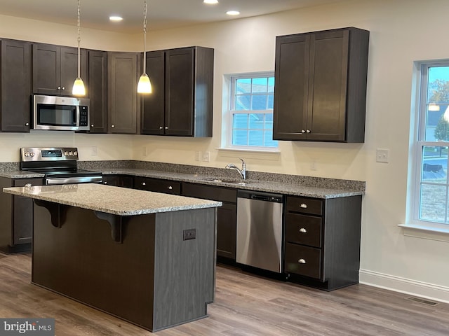 kitchen with stainless steel appliances, light hardwood / wood-style floors, sink, a kitchen breakfast bar, and a center island