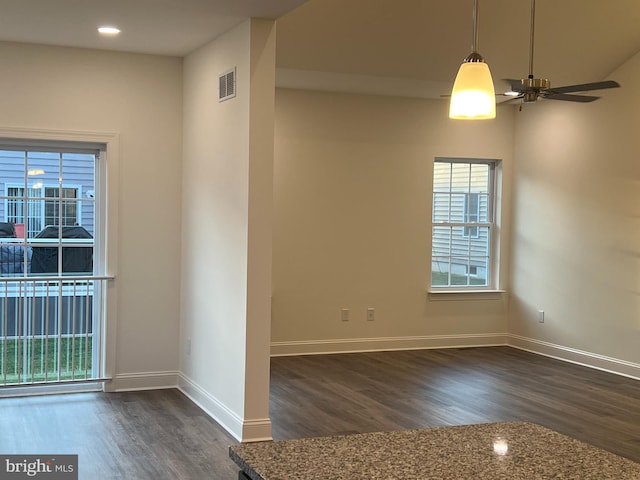 empty room with a wealth of natural light, ceiling fan, and dark hardwood / wood-style flooring