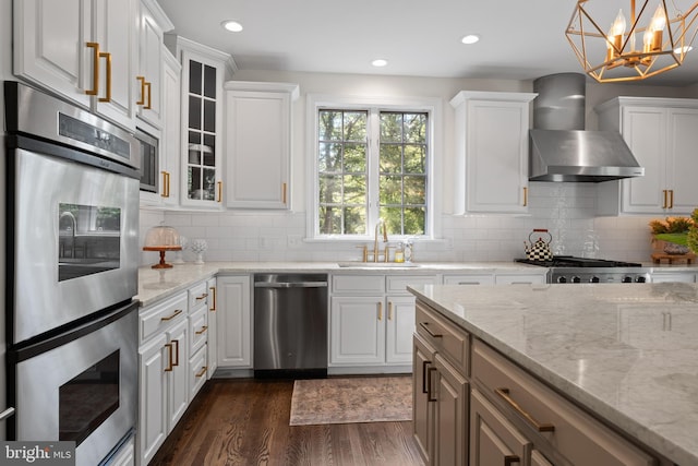 kitchen featuring white cabinetry, hanging light fixtures, wall chimney range hood, dark hardwood / wood-style flooring, and appliances with stainless steel finishes