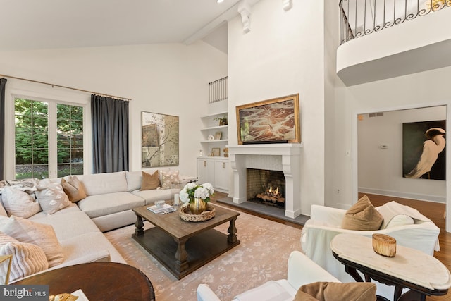 living room with beamed ceiling, high vaulted ceiling, and light hardwood / wood-style flooring