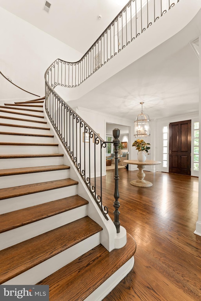 stairway with hardwood / wood-style floors and a notable chandelier