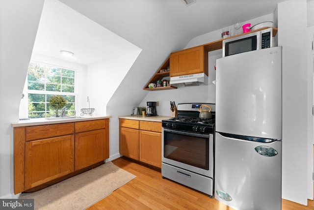 kitchen featuring sink, light hardwood / wood-style floors, lofted ceiling, extractor fan, and appliances with stainless steel finishes