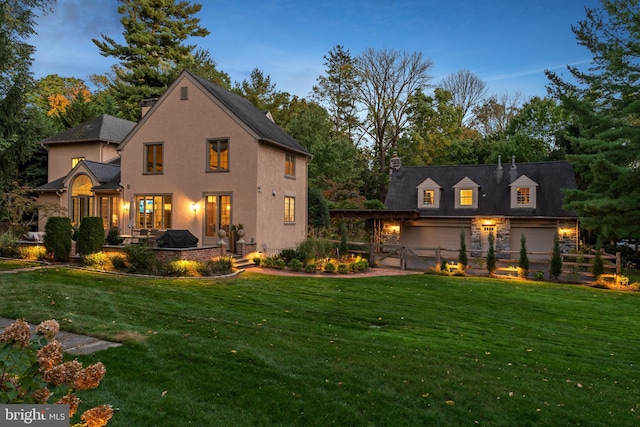 back house at dusk with a patio area and a yard