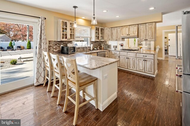 kitchen featuring sink, kitchen peninsula, tasteful backsplash, decorative light fixtures, and dark hardwood / wood-style flooring