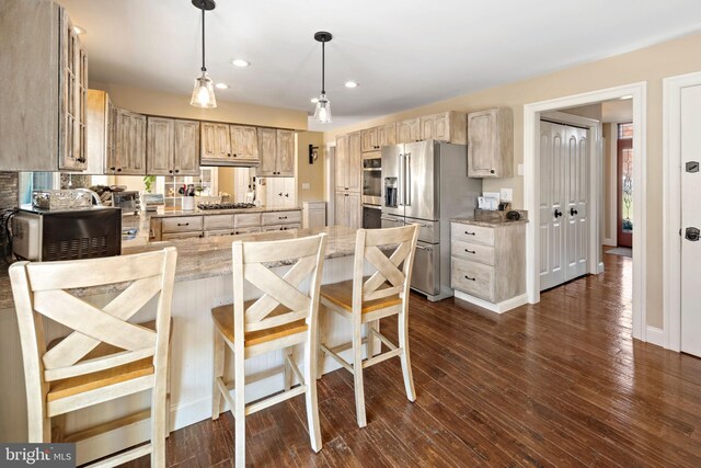 kitchen featuring hanging light fixtures, dark hardwood / wood-style floors, light stone countertops, appliances with stainless steel finishes, and light brown cabinetry