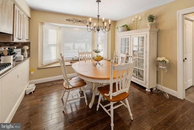 dining area featuring dark wood-type flooring and an inviting chandelier