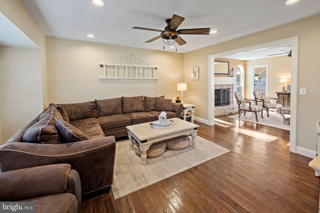 living room featuring dark hardwood / wood-style flooring, ceiling fan, and a fireplace