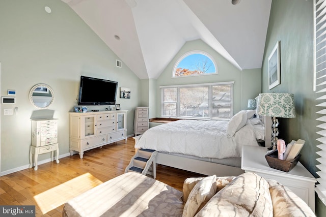 bedroom with high vaulted ceiling and light hardwood / wood-style floors